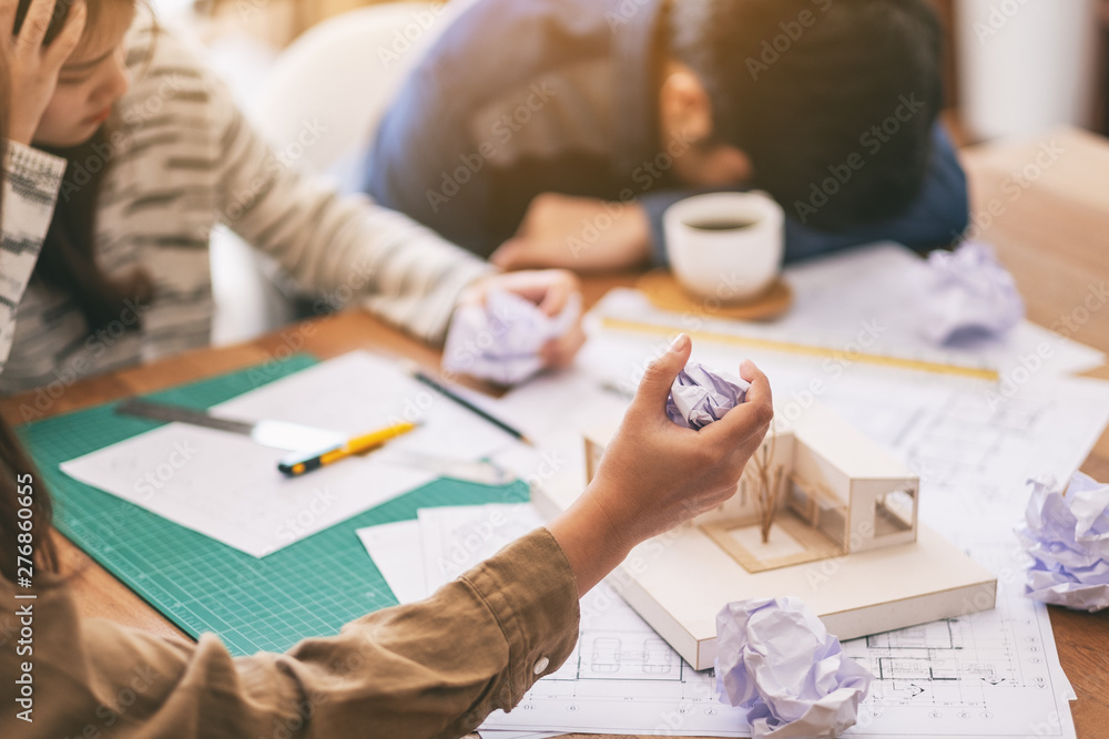Group of an architect feel stressed after working on architecture model together with shop drawing paper on table in office Group of an architect feel stressed after working on architecture model together with shop drawing paper on table in office