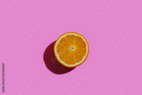 Fresh cutted orange on a colorful pink background at the center of the rectangular table