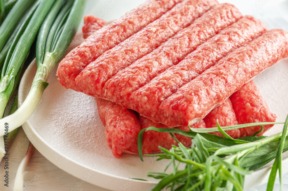 Chevapchichi is a national Balkan dish. Close up a row of fresh raw beef kebabs Chevapchichi is a national Balkan dish. Close up a row of fresh raw beef kebabs