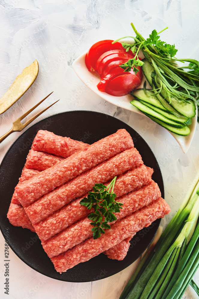 Chevapchichi is a national Balkan dish. Close up a row of fresh raw beef kebabs