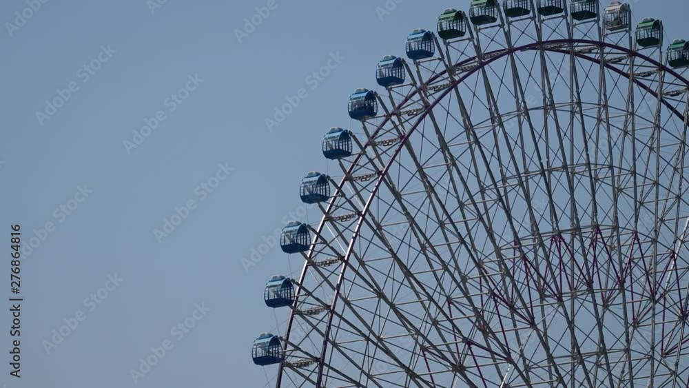 LOCKED OFF view of Ferris Wheel against blue sky background LOCKED OFF view of Ferris Wheel against blue sky background