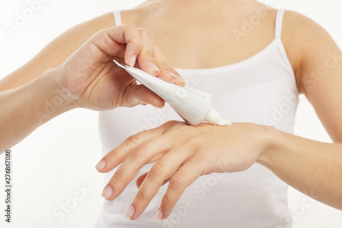 Closeup. The girl uses hand cream on a white background