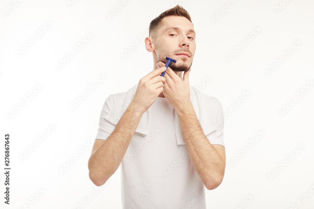Handsome man shaving his beard on a white background Handsome man shaving his beard on a white background