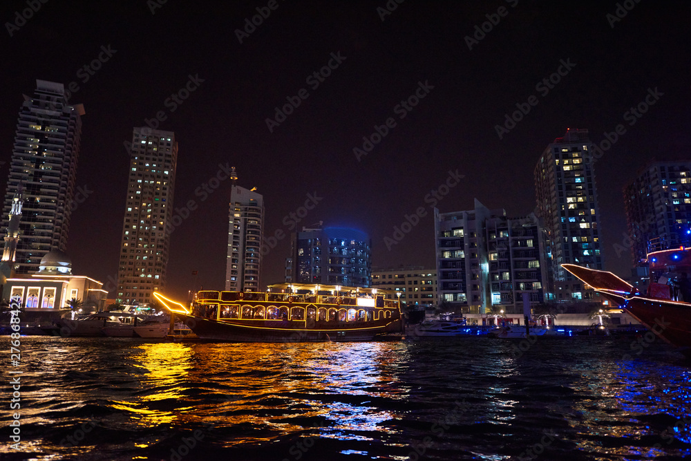Fototapeta premium Dubai Marina at night with colorful touristic boats