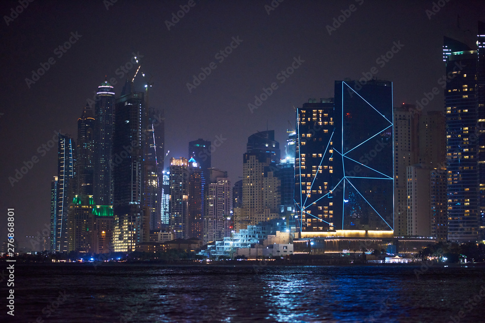 Naklejka premium Dubai Marina at night with colorful touristic boats