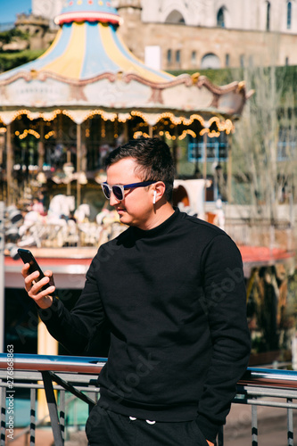 Young handsome man talking via headset standing in front of Tibidabo church. Travel concept. photo