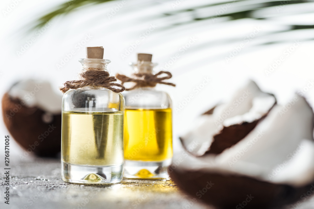 selective focus of bottles with coconut oil near cracked coconuts selective focus of bottles with coconut oil near cracked coconuts
