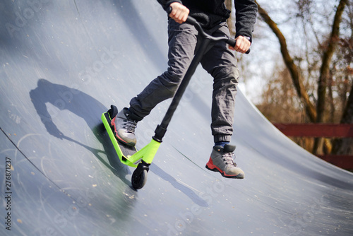 Photos Kid riding on stunt scooter on the skatepark ramp