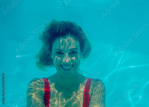 Underwater photograph of blonde girl with curls and red swimsuit.