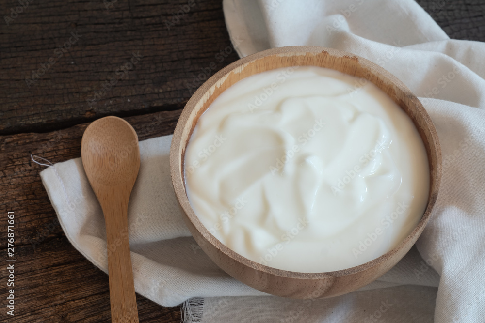 Natural homemade plain organic yogurt in wood bowl on wood texture background Natural homemade plain organic yogurt in wood bowl on wood texture background