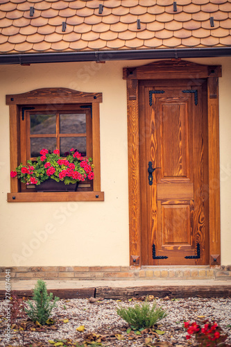 brown wooden window with flowers and wooden doors .
