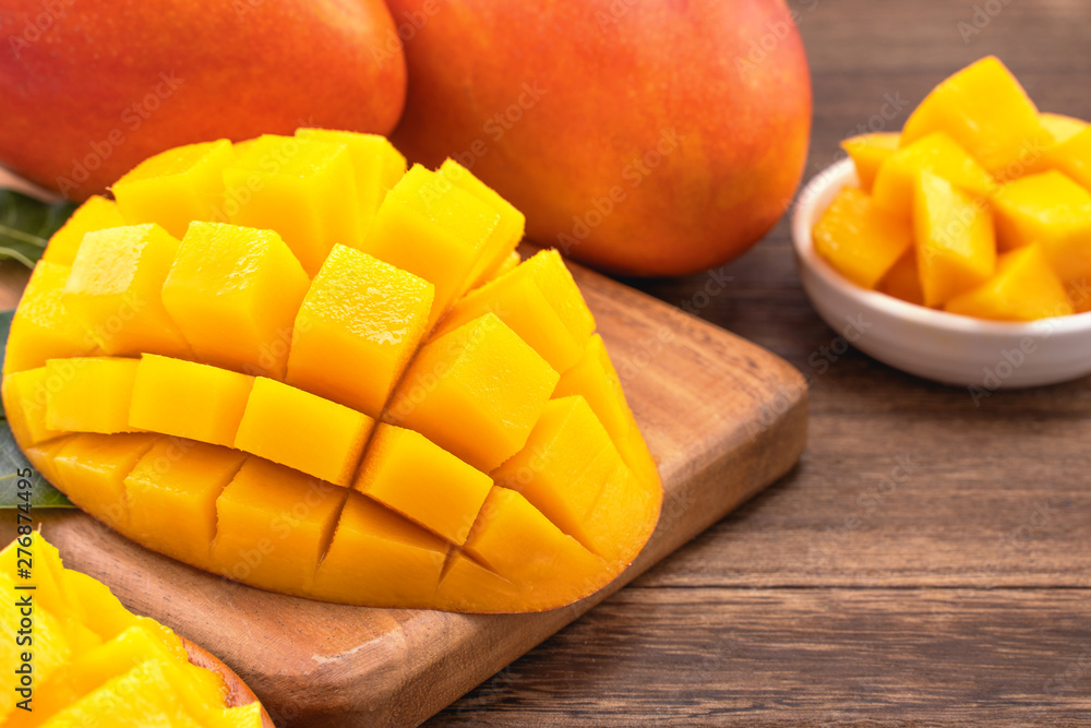 Fresh chopped mango cubes on wooden cutting board and rustic timber background. Tropical summer fruit concept, close up, macro, copy space. Fresh chopped mango cubes on wooden cutting board and rustic timber background. Tropical summer fruit concept, close up, macro, copy space.