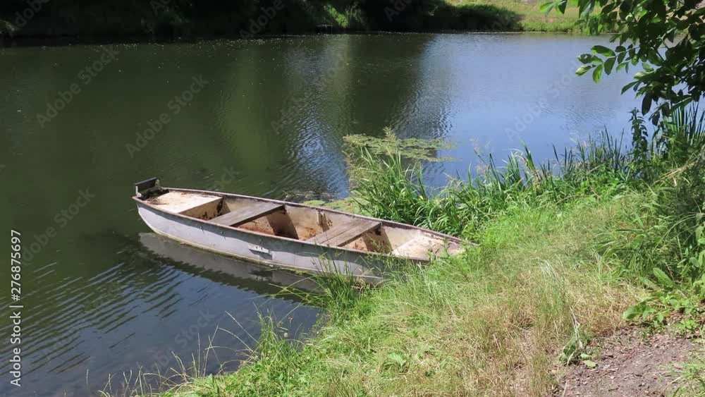 Empty white wooden boat anchored by a rope on a small lake used for relaxation and fishing Empty white wooden boat anchored by a rope on a small lake used for relaxation and fishing