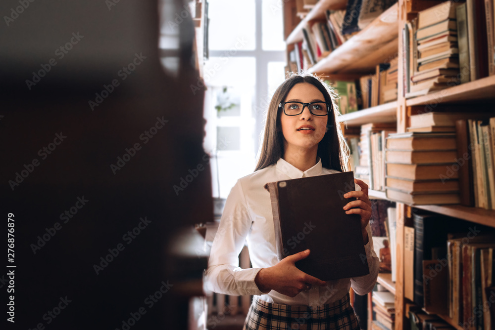 people, knowledge, education and school concept - happy student girl with book in library