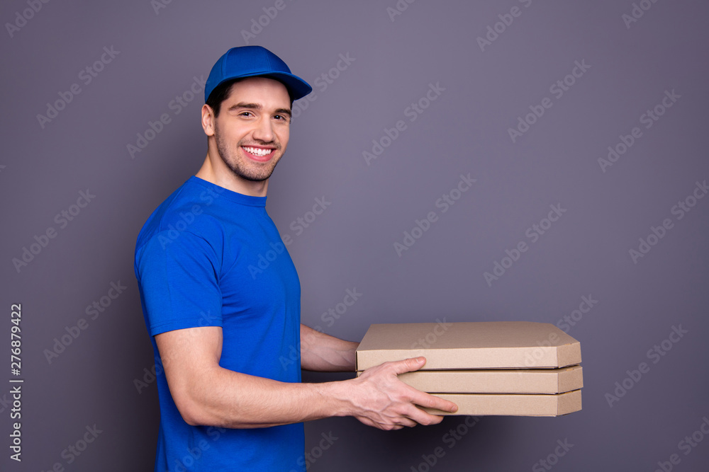 Close up side profile photo express speed specialist he him his delivery boy hold strong arms three parcel boxes toothy come in time wear blue t-shirt cap corporate suit isolated grey background Close up side profile photo express speed specialist he him his delivery boy hold strong arms three parcel boxes toothy come in time wear blue t-shirt cap corporate suit isolated grey background