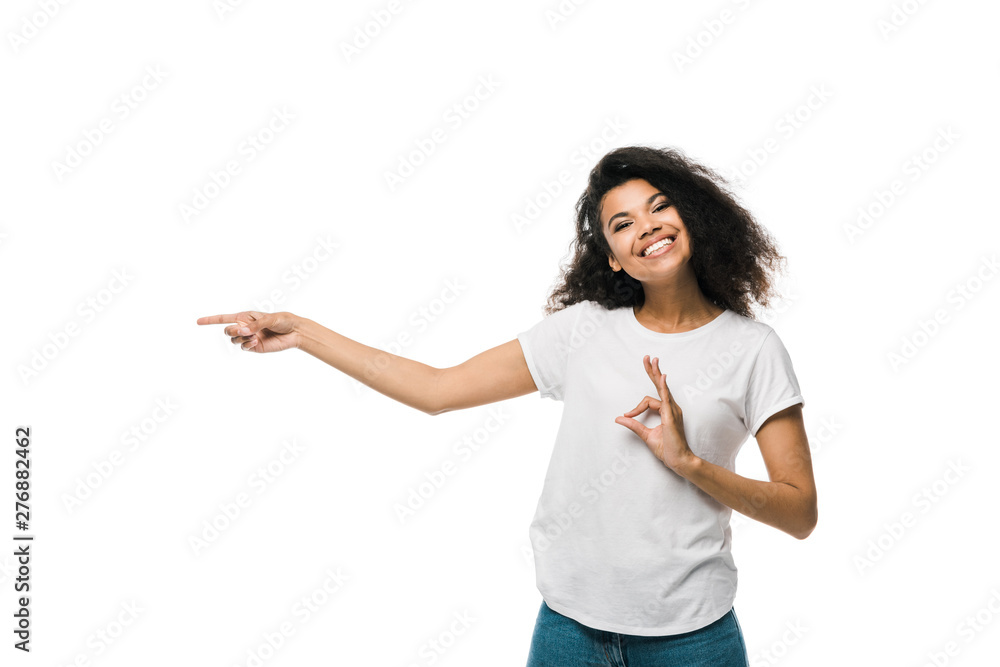 happy african american woman pointing with finger while showing ok sign isolated on white happy african american woman pointing with finger while showing ok sign isolated on white