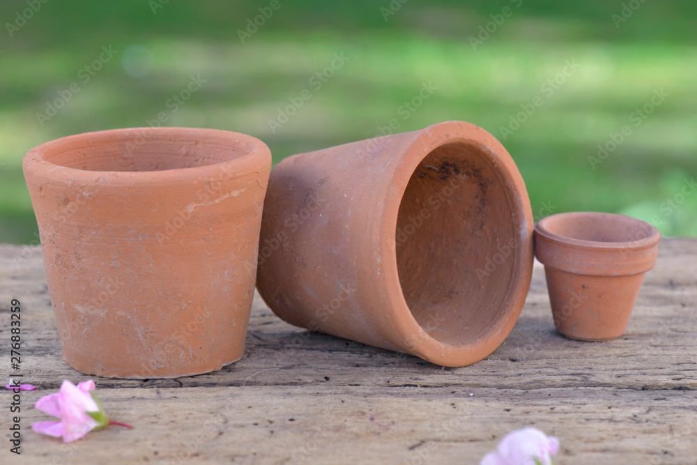group of terracotta flowerpots put on wooden table in a garden group of terracotta flowerpots put on wooden table in a garden