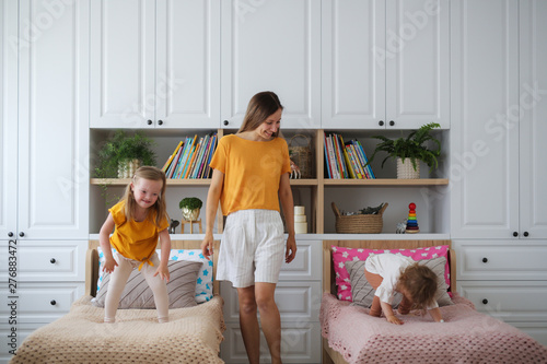 Children siblings jump on beds near their mother