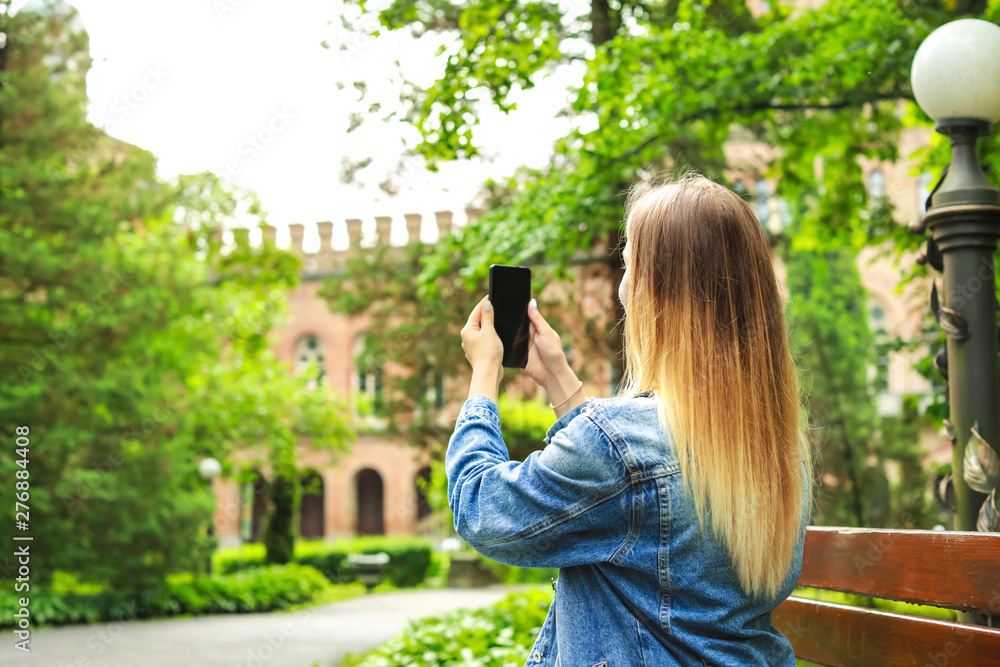 Naklejka premium Female tourist taking photo in beautiful park