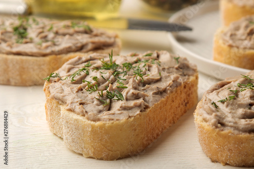 Fresh homemade chicken liver pate with herbs for bread on a white wooden table. A sandwich. close-up