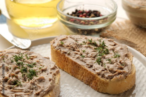 Fresh homemade chicken liver pate with herbs for bread on a white wooden table. A sandwich. close-up