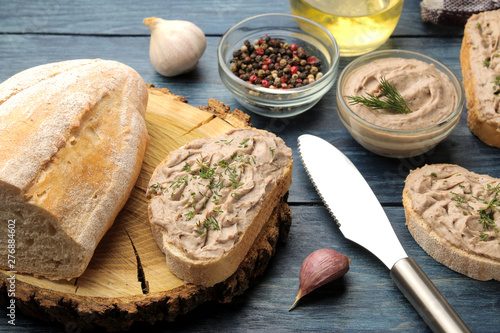 Fresh homemade chicken liver pate with herbs on bread on a blue wooden table. A sandwich.