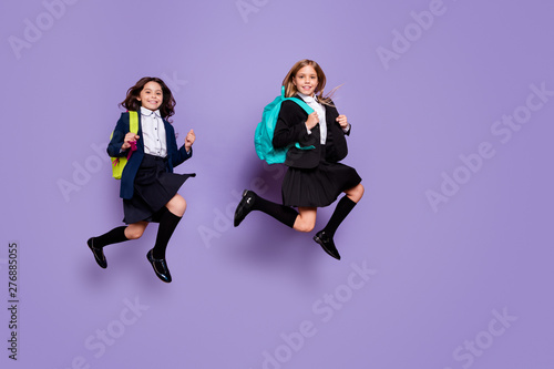 Full length photo of charming children wear skirt long socks go school isolated over purple background