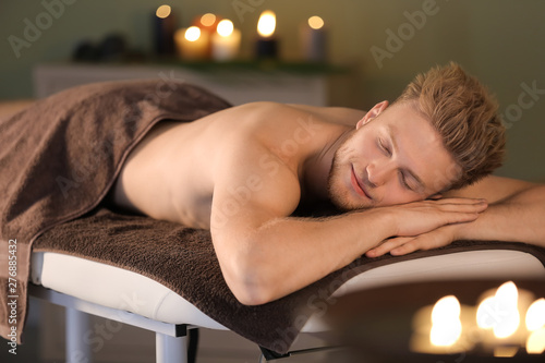 Handsome young man relaxing in spa salon