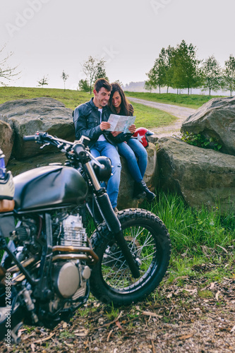 Young couple sitting looking at a map during a motorcycle trip