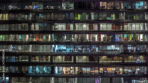 Working evening in glass office building with numerous offices with glass walls and windows timelapse