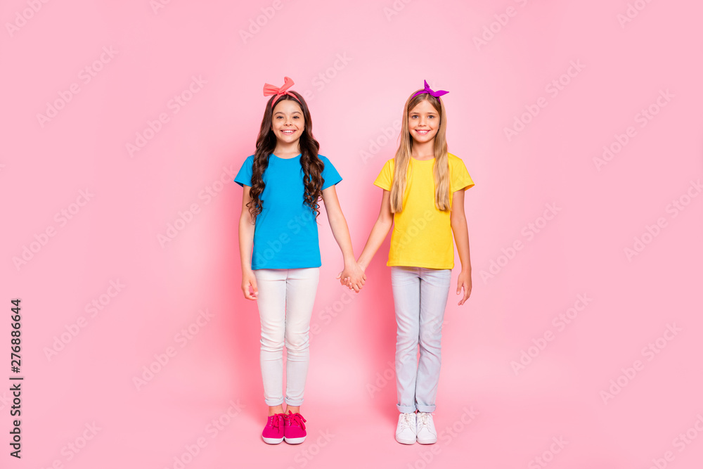 Full length body size view of two nice-looking winsome attractive charming cute lovely friendly cheerful cheery pre-teen girls holding hands spending time isolated over pink pastel background Full length body size view of two nice-looking winsome attractive charming cute lovely friendly cheerful cheery pre-teen girls holding hands spending time isolated over pink pastel background