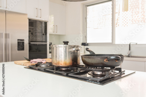 Closeup of frying pan and large pot on gas stove top in modern kitchen (selective focus)