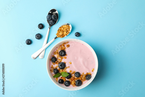 Yogurt with granola  blueberry and mint on color background