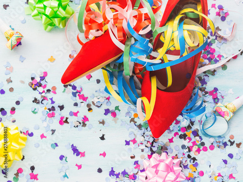 Flat lay background with woman's red pump shoes, colorful confetti, streamers. Party or sale concept.