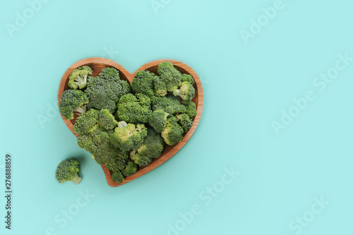 Heart shaped fresh green broccoli on wooden plate isolated on white.