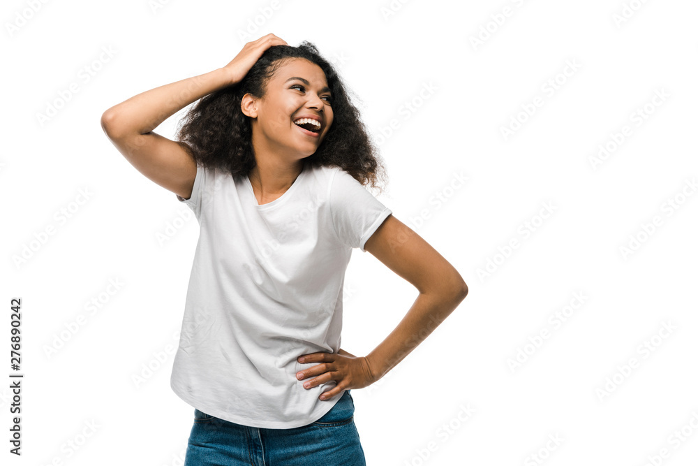happy curly african american woman touching hair while standing with hand on hip isolated on white happy curly african american woman touching hair while standing with hand on hip isolated on white