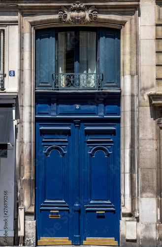 Door of old house. Antique front door of old building in Paris France. Vintage blue painted wooden doorway with ornate framed panels and stone weathered wall of ancient house in classical architecture © Ninel