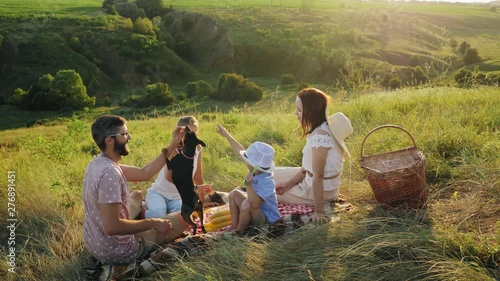 Family spending time together on a picnic with their dog photo