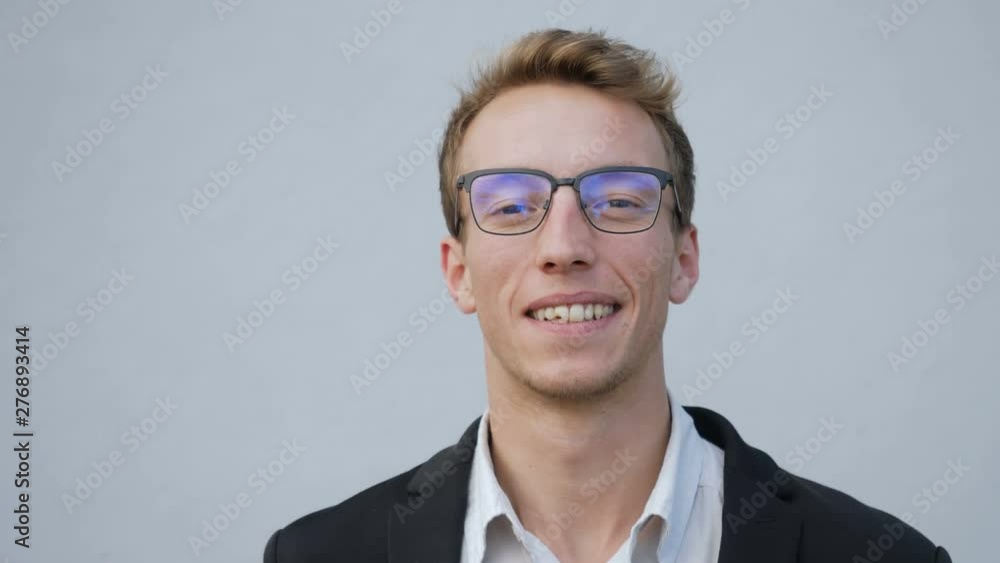 Front view of smiling young Caucasian male face in spectacles standing outside, looking at camera. Lifestyle concept Front view of smiling young Caucasian male face in spectacles standing outside, looking at camera. Lifestyle concept