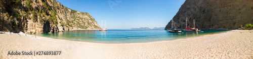 Sailing ships moored in a secluded bay with turquoise water and empty beach at sunrise, Oludeniz, Turkey panoramic