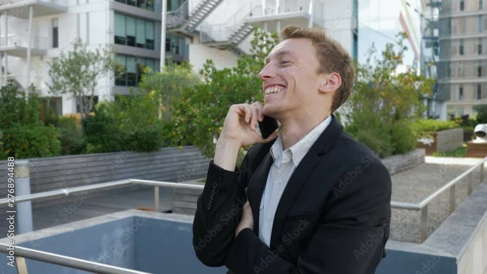 Happy young Caucasian man talking on phone outside business office, smiling, looking excited. Lifestyle, communication concept Happy young Caucasian man talking on phone outside business office, smiling, looking excited. Lifestyle, communication concept