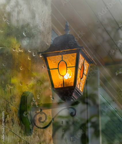 Decorative street lamp seeen trough the window, water drops after rain, selective focus photo