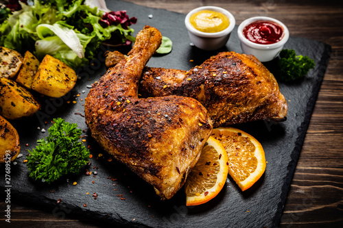 Roast chicken legs on black stone plate photo