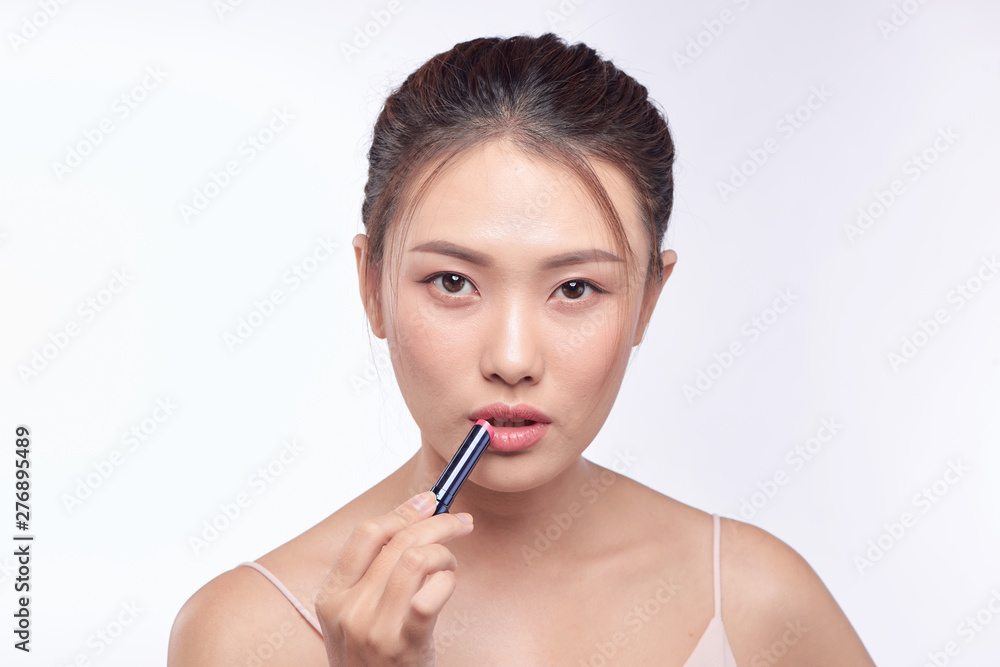 Pretty asian woman applying lipstick, isolated on white Pretty asian woman applying lipstick, isolated on white