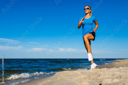 Young woman running, jumping on beach photo