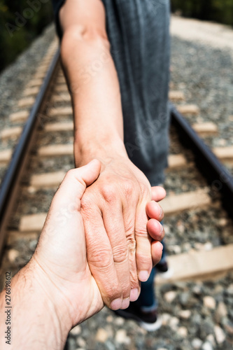 men holding hands on the railroad tracks