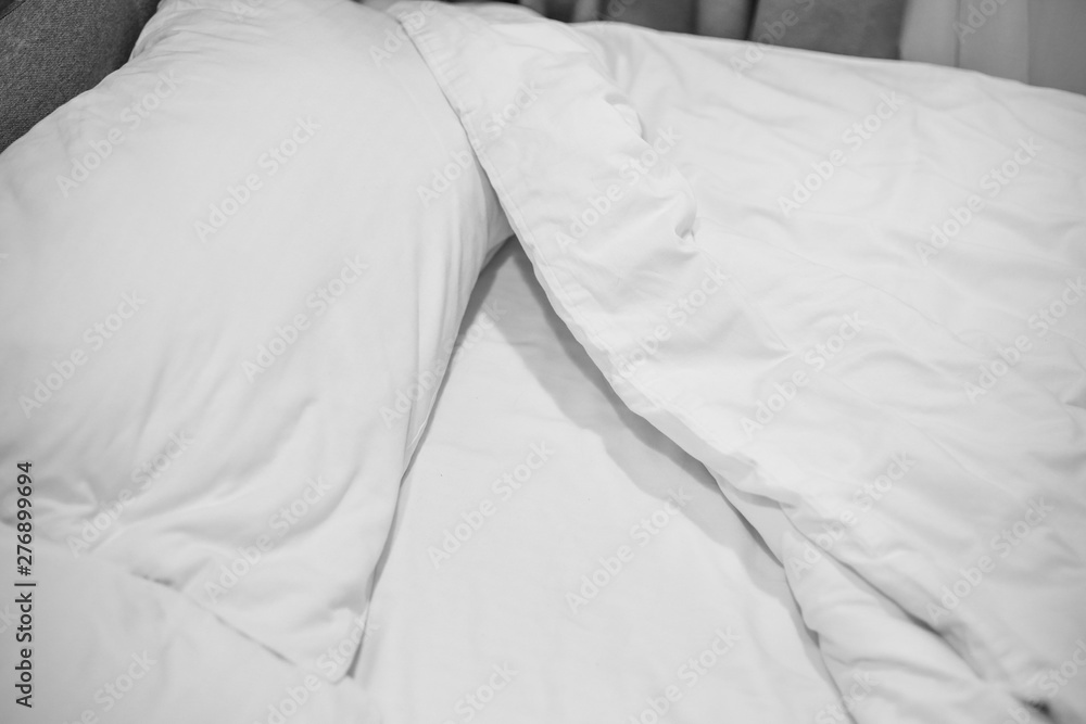 Close up white bedding sheets and pillow on natural stone wall room background, Messy bed concept Close up white bedding sheets and pillow on natural stone wall room background, Messy bed concept