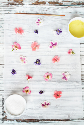 Ingredients for making homemade sugared or crystallized edible flowers on a white wooden rustic table. Image shot for above. photo