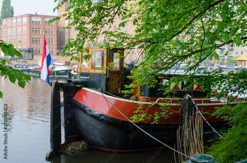 moored old retro ship with the flag of the Netherlands on the channel in the Amsterdam.