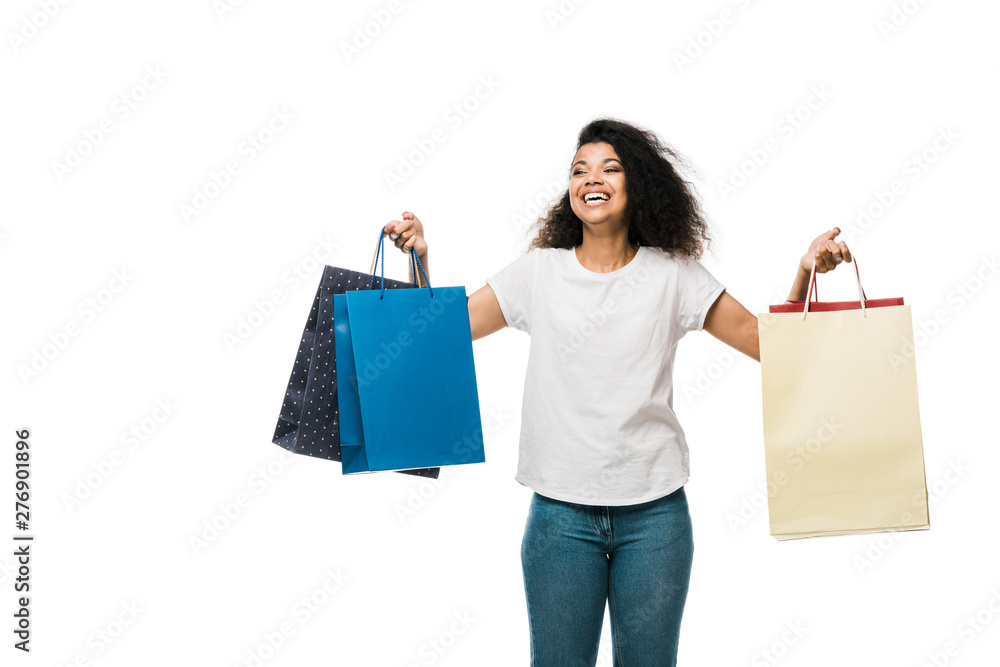 positive african american girl holding shopping bags while standing isolated on white positive african american girl holding shopping bags while standing isolated on white